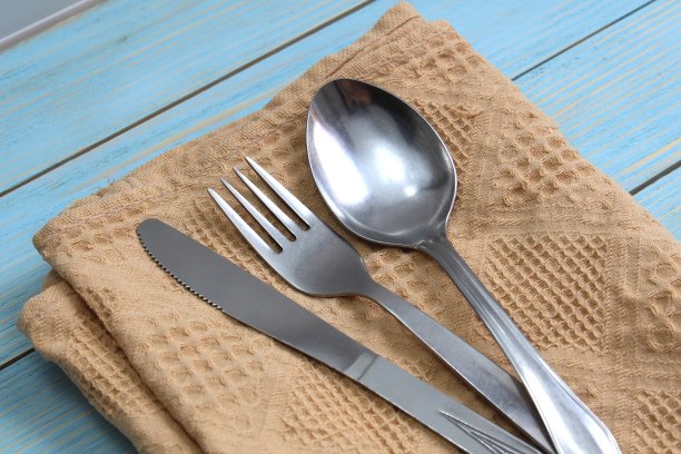 勺子，叉子和刀放在一张木桌上的餐巾上。图片下载