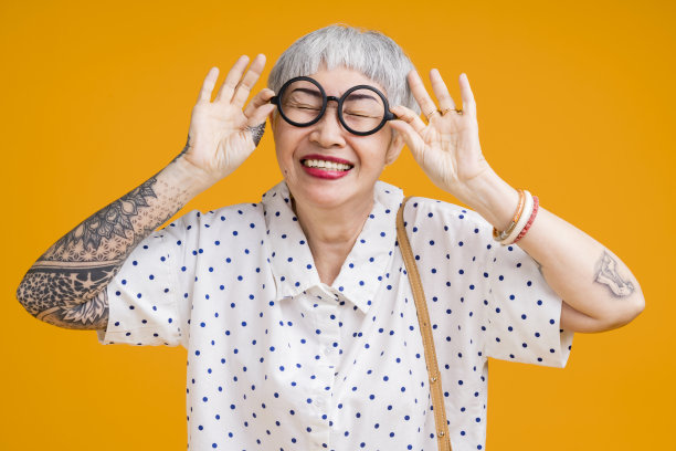 有吸引力的时髦的亚洲纹身的肖像开朗的白发老人老年妇女触摸眼镜孤立在黄色粉彩的背景色，惊喜和过度兴奋的感觉表达图片下载