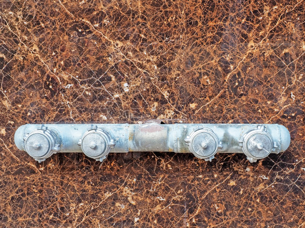 消防水泵头在墙上。在大理石棕色图案的墙上连接消防水管的金属头。图片下载
