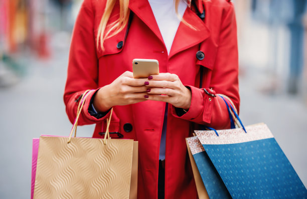 女子在城市购物时使用手机，特写照片。消费主义生活方式的概念图片下载
