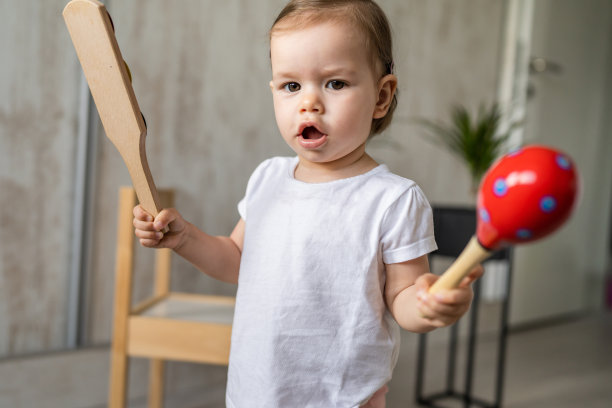 一个女孩小白人孩子小蹒跚学步的孩子在家里玩木制拨浪鼓玩具拷贝空间图片下载