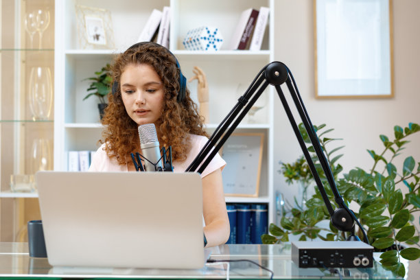 年轻的卷发女性录制播客从家里，对着麦克风说话图片下载