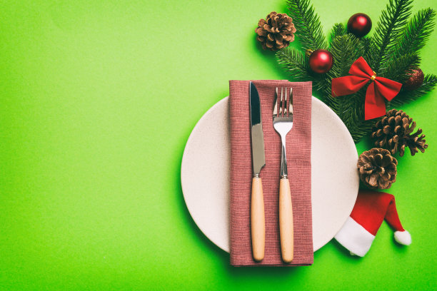 圣诞餐桌布置圣诞装饰和盘子，牛，叉子和勺子。圣诞节的背景。带有拷贝空间的俯视图图片下载