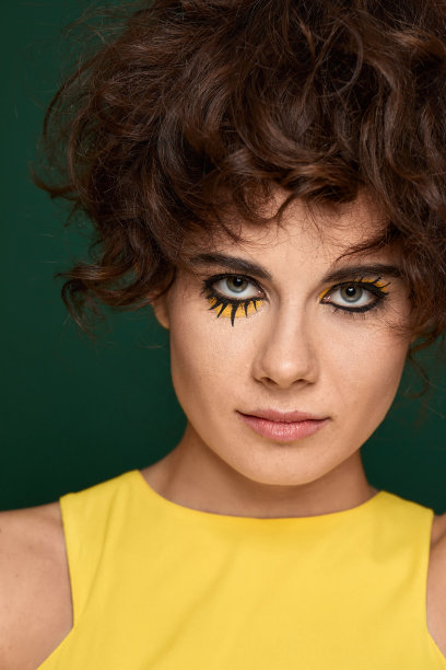 年轻卷曲的女人与创意化妆在黄色连衣裙图片下载