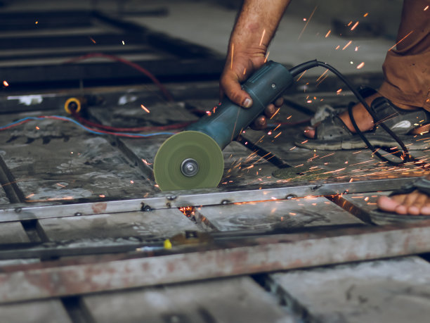 工人用手切割机切割金属框架，圆盘切割机切割火花图片下载