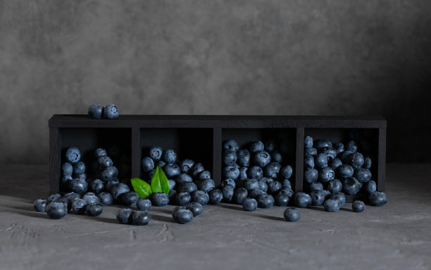 蓝莓散落在灰色背景的黑色盒子里。有拷贝空间的蓝莓。图片下载