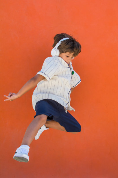 一个在橙色背景上跳跃的孩子。图片下载