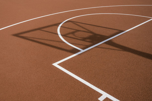 阳光明媚的户外，在橙色的篮球橡胶场上的篮球架和篮球圈的影子。篮球比赛的背景图片下载