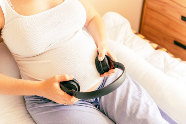 怀孕治疗音乐。听音乐的孕妇。妈妈肚子听耳机的声音。孕产期、医药保健和人的观念。图片下载