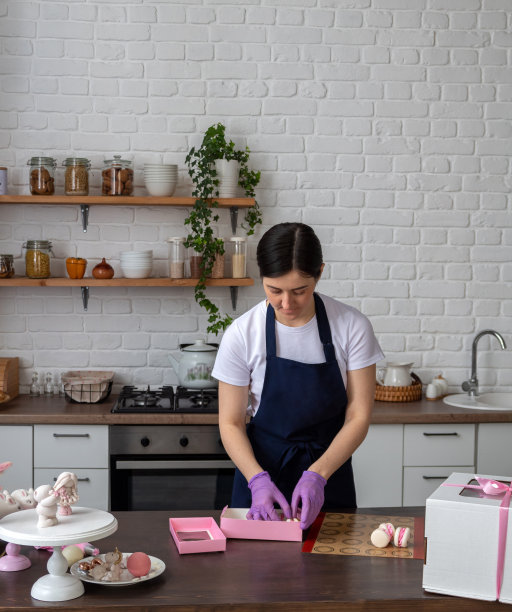 戴手套的糕点师把新鲜的马卡龙装在送货盒里放在桌子上。有选择性的重点。有关糖果、食品配送的网站图片。图片下载