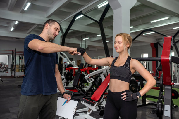 私人男性教练帮助女性用沉重的哑铃锻炼图片下载