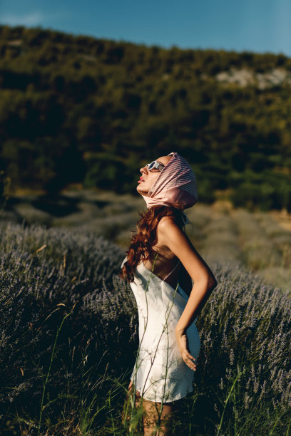 性感的时尚女人在白色连衣裙摆在盛开的薰衣草田在日落图片下载