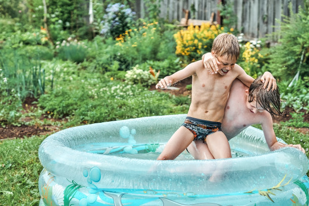 兄弟俩在院子里的儿童充气泳池里摔跤图片下载