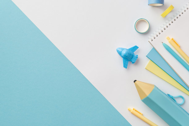 学习用品的概念。俯视图照片的黄色和蓝色学校配件飞机形状的卷笔刀笔记本笔胶带和铅笔盒双色蓝色和白色的背景与copyspace图片下载