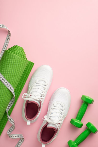 健身器材的概念。俯视图垂直照片的白色运动鞋运动垫卷尺和哑铃在孤立的粉彩粉红色的背景图片下载