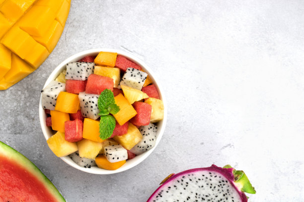 热带水果沙拉:芒果，火龙果，菠萝和西瓜在灰色的背景，俯视图。副本的空间。泰国的水果沙拉。图片下载