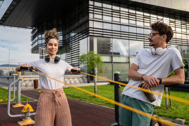 年轻夫妇白种男人和女人的男朋友和女朋友或丈夫和妻子在户外开放的健身房教练提供运动建议弹性电阻管锻炼拷贝空间图片下载