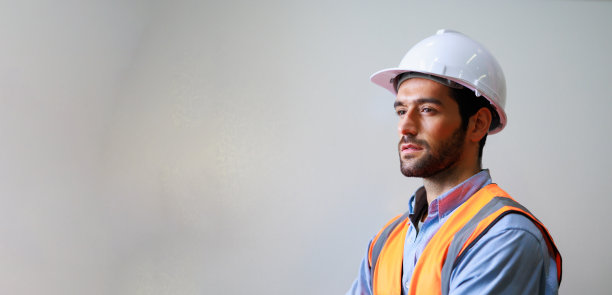 肖像专业机械工程西班牙裔男性在白色安全安全帽头盔和看镜头在金属工厂。专业工业仓库图片下载