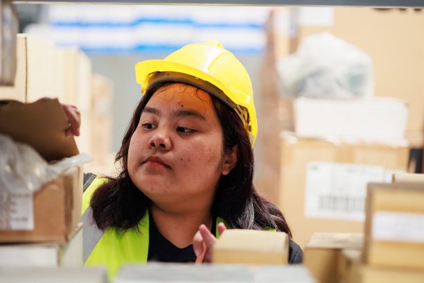 亚洲肥胖女仓库工人在安全背心和安全帽在仓库工厂工业。产品装在纸箱里放在货架上。加上尺码女性在工作时检查产品图片下载