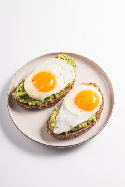 牛油果鸡蛋三明治加一杯水。健康清淡的早餐理念。全谷物吐司配牛油果泥和煎蛋图片下载