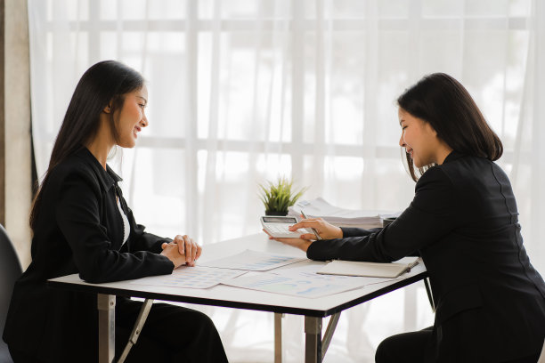 两个年轻的亚洲商人在办公室讨论投资营销，并介绍新的创业项目想法。分析、计划并绘制财务统计图。图片下载