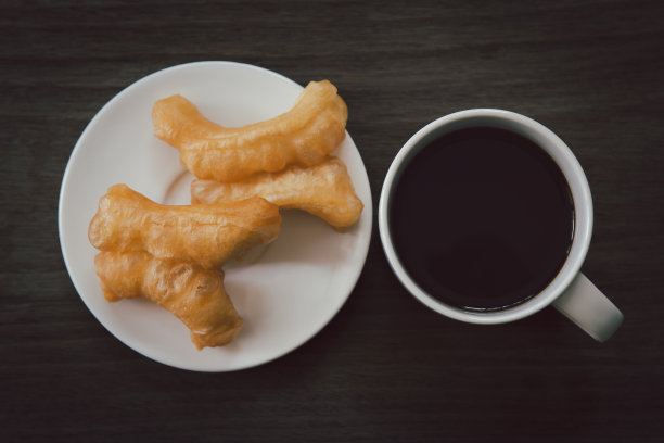 黑咖啡和油条放在木桌上。图片下载