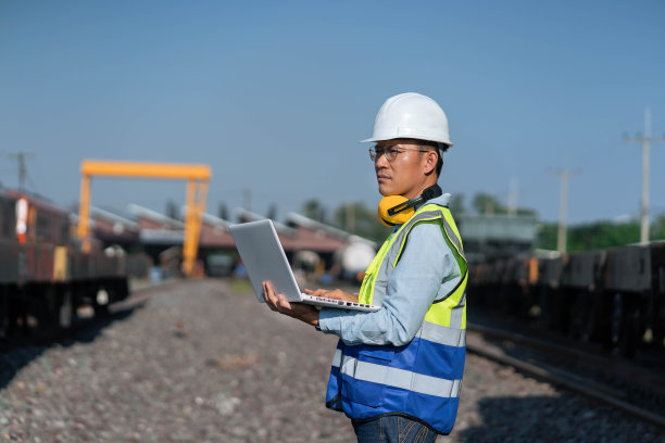 头戴钢盔、身穿制服的工程师，用手提电脑制定计划的工程师，在火车站工作的工程师。图片下载