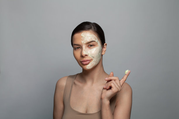 时尚美女肖像可爱的女人与化妆品面具在灰色的背景图片下载