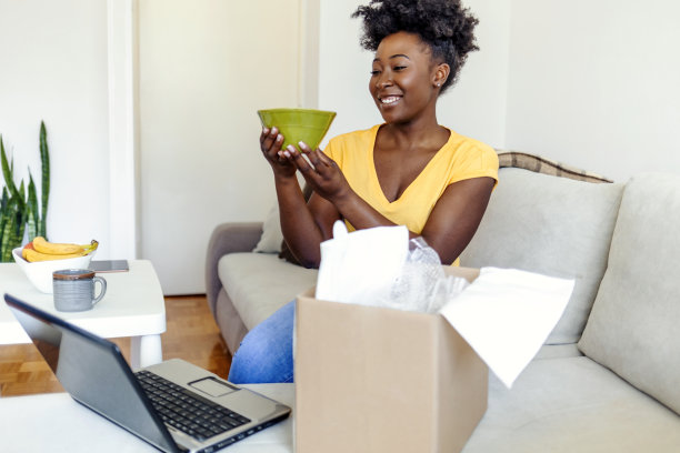 女性消费者打开包裹接收零售购买快速邮政快递的概念。女人在家打开网购的箱子，看着她的新礼物。图片下载