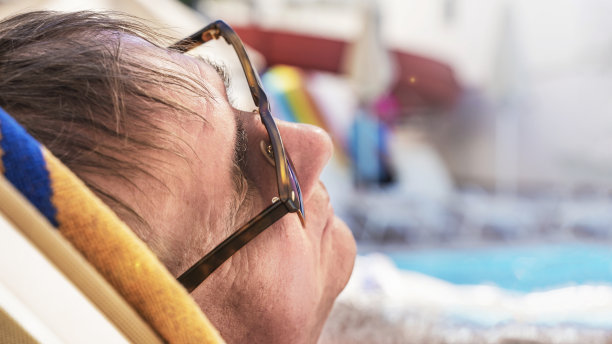 戴着眼镜在海滩上晒日光浴的老人图片下载