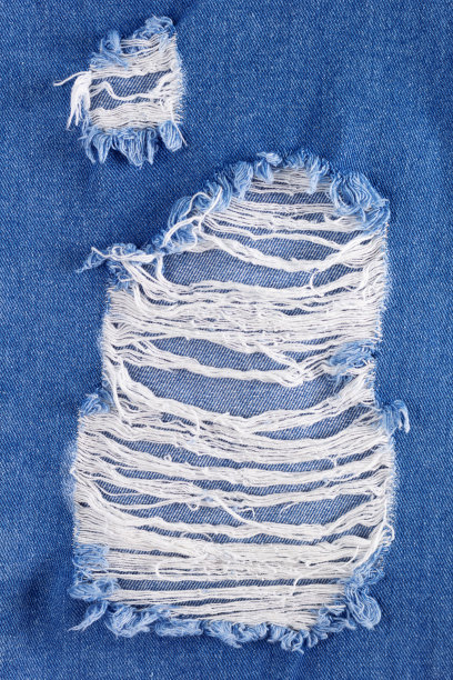 蓝色牛仔裤牛仔的背景质感。牛仔裤面料材料表面撕裂图片下载