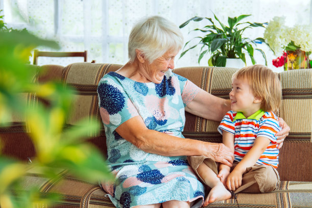 多代人的家庭游戏时间。老年妇女抱着小婴儿可爱地笑着。快乐的祖母和她的孙子在家里玩得很开心。图片下载