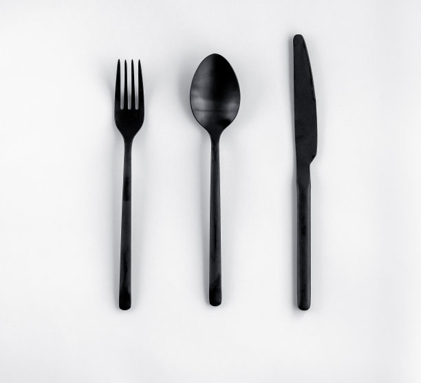 黑色的叉子，勺子，刀单独放在白色的上面。图片下载