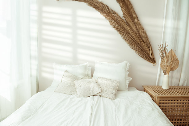 靠近自然明亮的卧室内部，舒适的床覆盖着白色的床单。舒适卧室的hygge室内概念。环保的家居装饰和干燥的植物图片下载