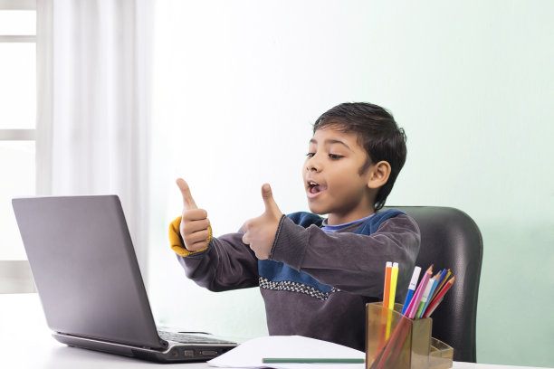 男孩在家中学习时使用笔记本电脑并在视频通话中挥手图片下载