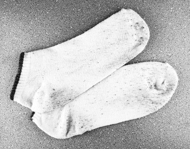 又脏又旧的袜子没有颜色。脏白袜子。脏袜子沾在浴室瓷砖上。图片下载