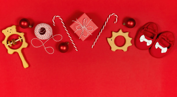 圣诞特卖婴儿和幼童用品横幅。拨浪鼓，靴子，圣诞礼物和玩具的广告横幅或网站标题。婴儿圣诞横幅在红色背景与复制空间。图片下载