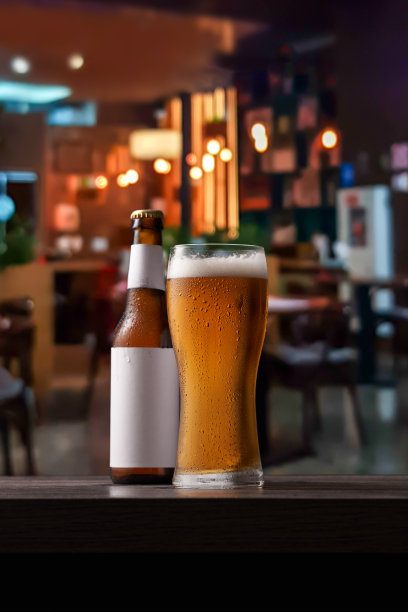酒吧柜台上的一瓶和一杯啤酒。图片下载