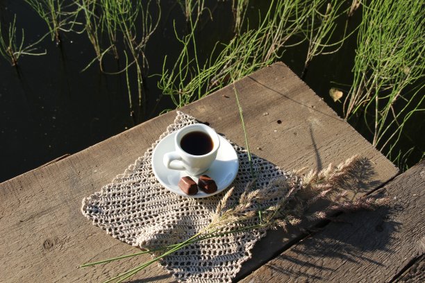 夏日清晨，咖啡，糖果，河边木桥上的林花图片下载