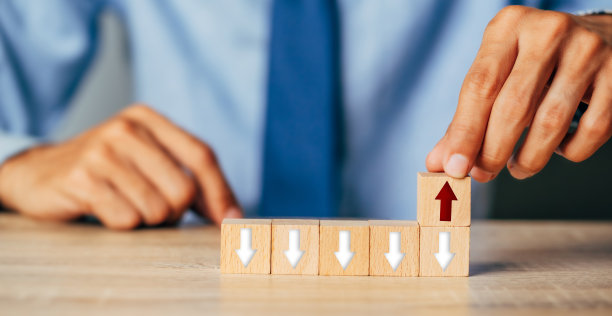 用手将木块堆叠成阶梯楼梯，箭头向上。阶梯职业道路为企业成长成功的过程概念。图片下载