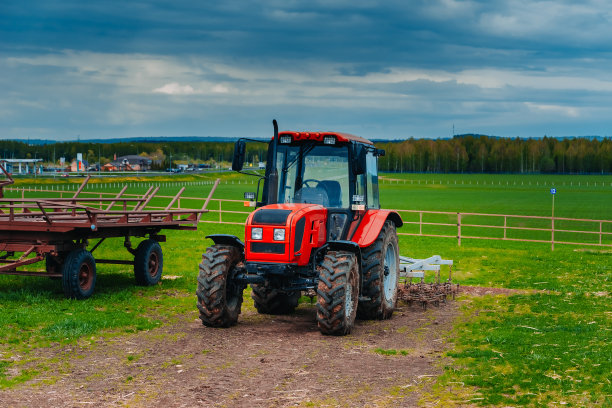 乡村风景中的红色拖拉机。用拖拉机在田间收割干草图片下载