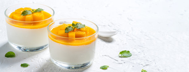 美味的双色芒果意式奶冻慕斯布丁在白色的桌子背景。图片下载