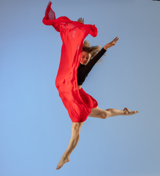 舞者在蓝色背景和红色面料上跳跃图片下载