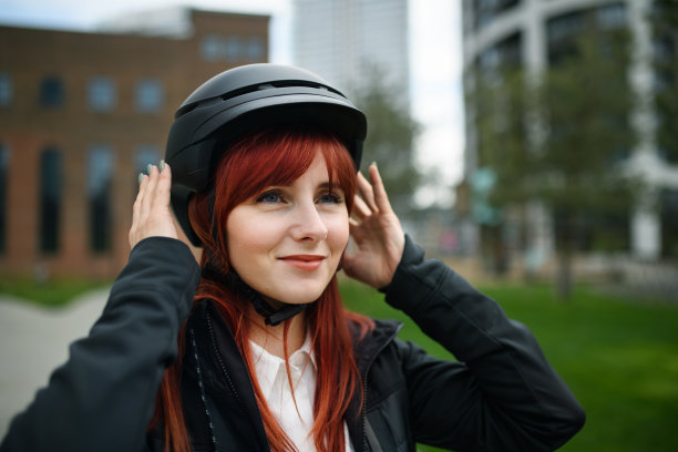 肖像的女商人通勤在上班的路上戴上自行车头盔，可持续的生活方式的概念。图片下载