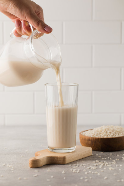 蔬菜米奶从罐子里倒进玻璃杯里。替代牛奶。图片下载