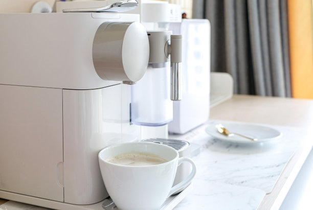 在咖啡机下酿造的白色咖啡杯。一台现代化的家庭/办公室咖啡机图片下载