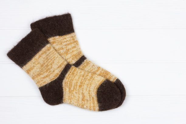 温暖的男人白色针织狗毛袜子在白色木制背景与复制空间，顶视图图片下载