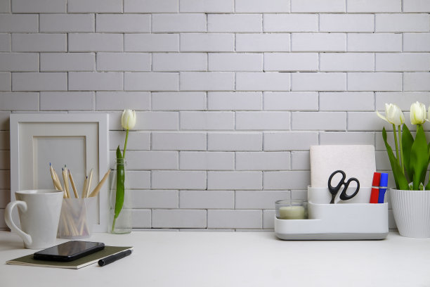 时尚的工作场所，有相框，咖啡杯，盆栽和白色桌子上的用品。副本的空间。图片下载