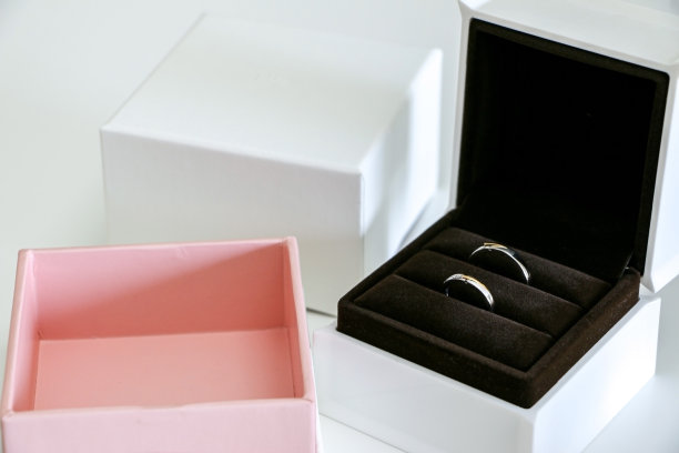 一对美丽闪亮的结婚戒指在开放的盒子旁边漂亮的白色和粉红色的包装。浪漫、爱情和婚姻的概念。图片下载