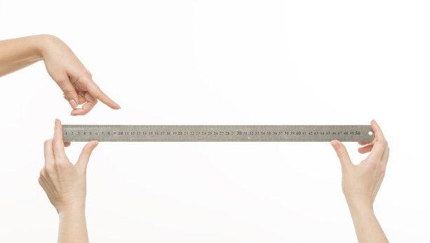 双手拿着尺子在一个孤立的白色背景上测量东西。图片下载